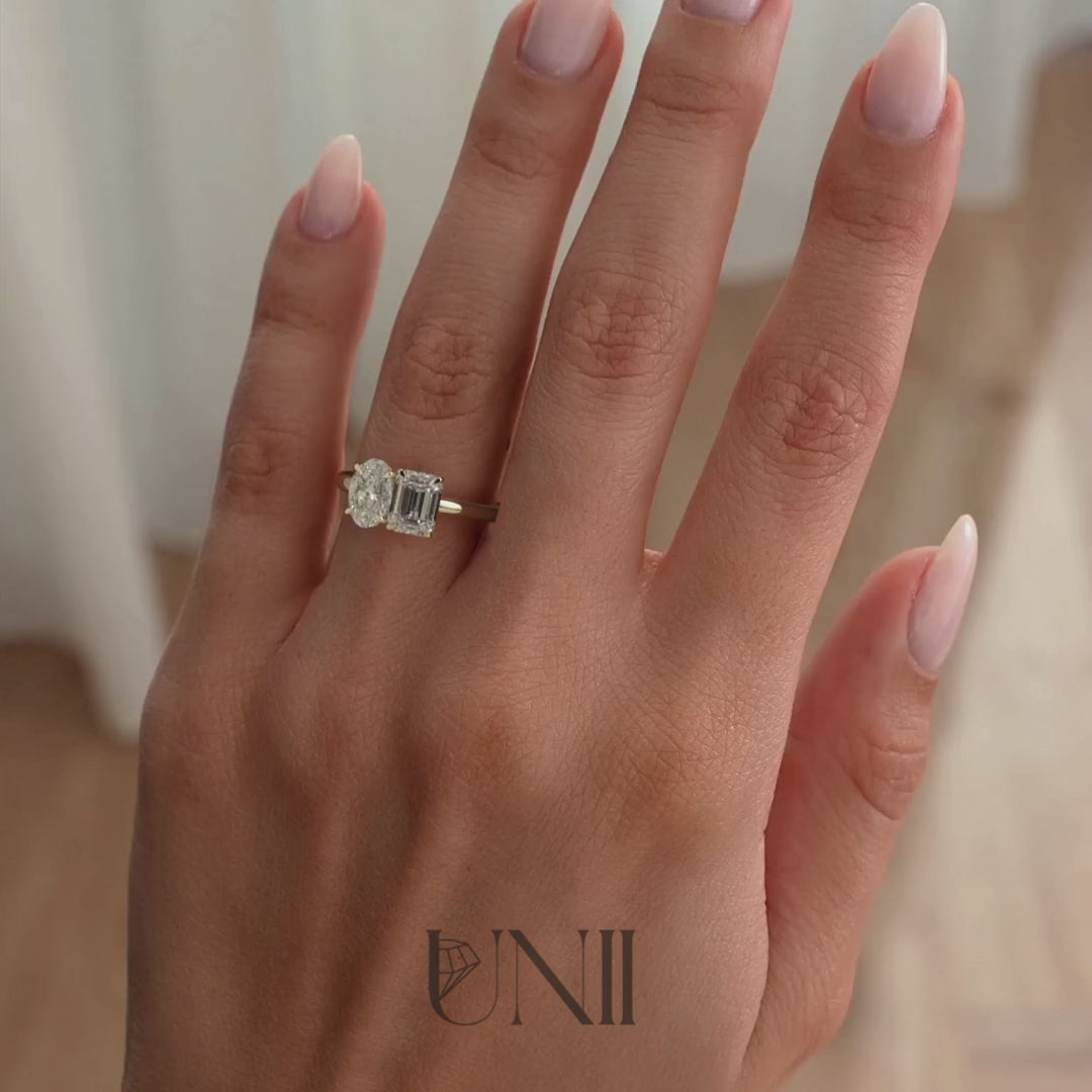 Yellow :: Classic oval and emerald lab grown diamond toi et moi engagement ring in yellow gold featuring IGI certified diamonds. A timeless two-stone design combining brilliance and structure, symbolizing unity and modern romance.