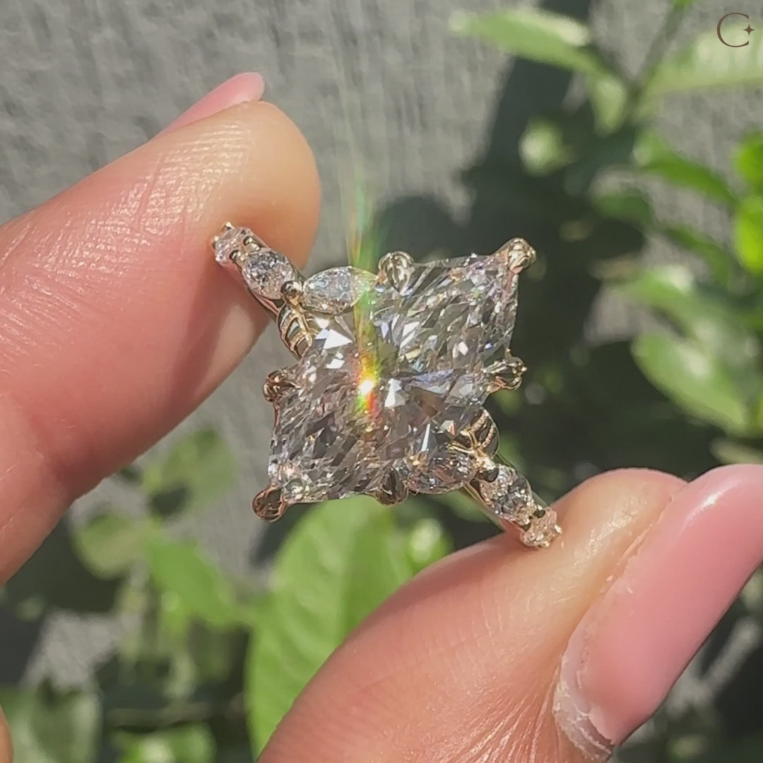 Common :: Close-up of a marquise cut lab grown diamond ring showcasing botanical leaf details and sparkling side diamonds.